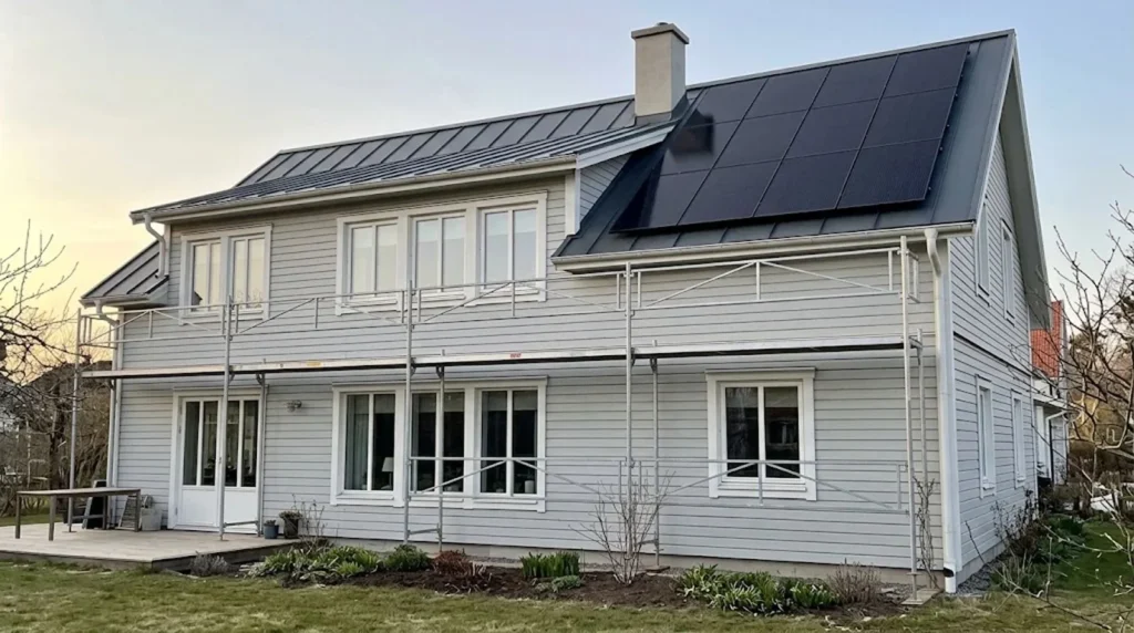 Installatör kopplar solpaneler i strängar på ett villatak